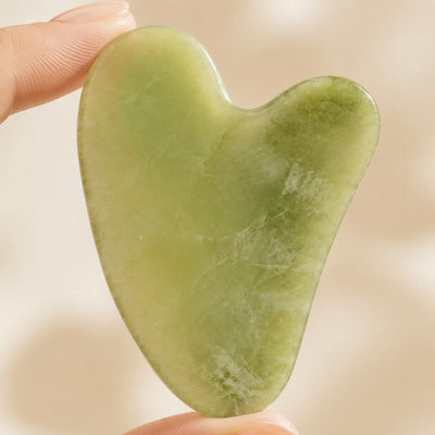 Gua-Sha-Stein zwischen Fingerspitzen im Detail